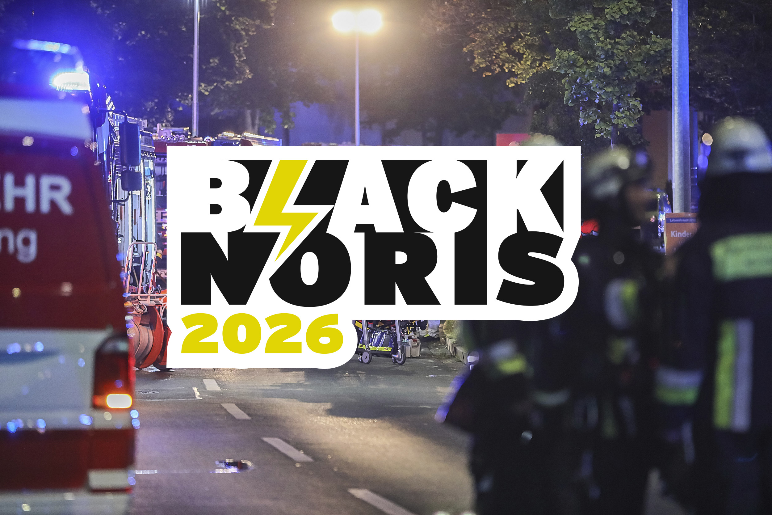 Schriftzug „BLACK NORIS 2026“ mit Blitzsymbol vor einem nächtlichen Feuerwehreinsatz. Im Hintergrund sind Einsatzfahrzeuge, Blaulicht und Feuerwehrkräfte auf einer Straße zu sehen.